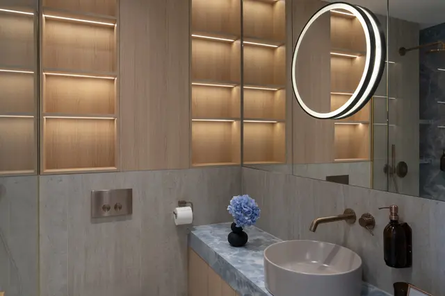 Bathroom vanity in stone and brass with backlit oak shelving