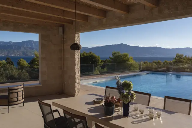 The long table set, pool and sea through the stone arches