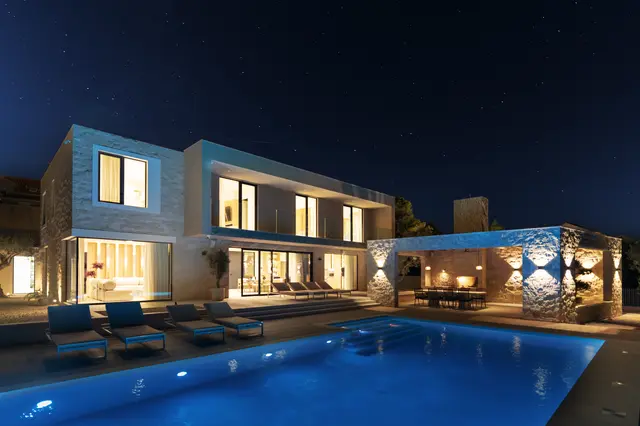 Villa Danica lit at night, the pool glowing beside the house